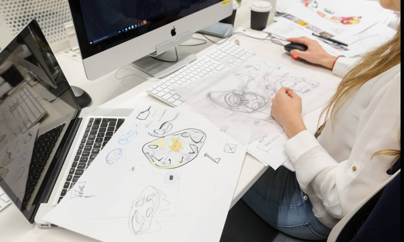 A desk with sketches on top of a laptop
