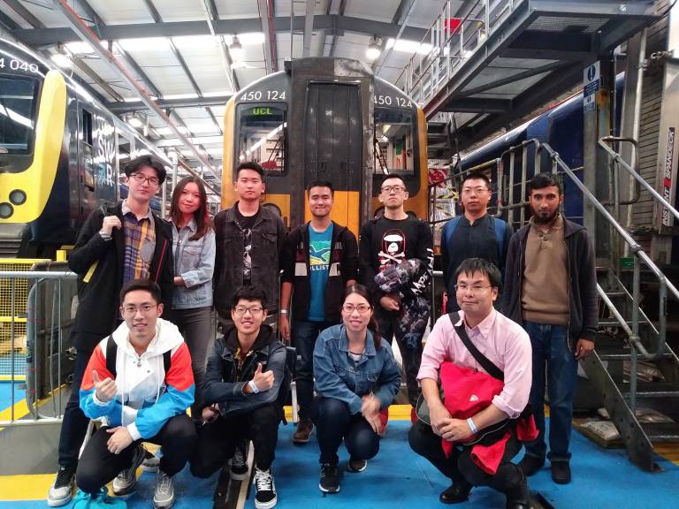 UCL students and staff pose in front of a train in a depot.
