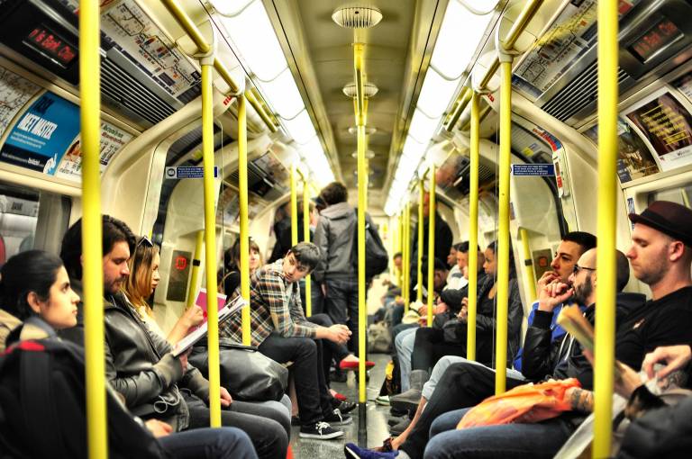 A shot of a London Underground tube carriage with people sat down, reading and looking round.