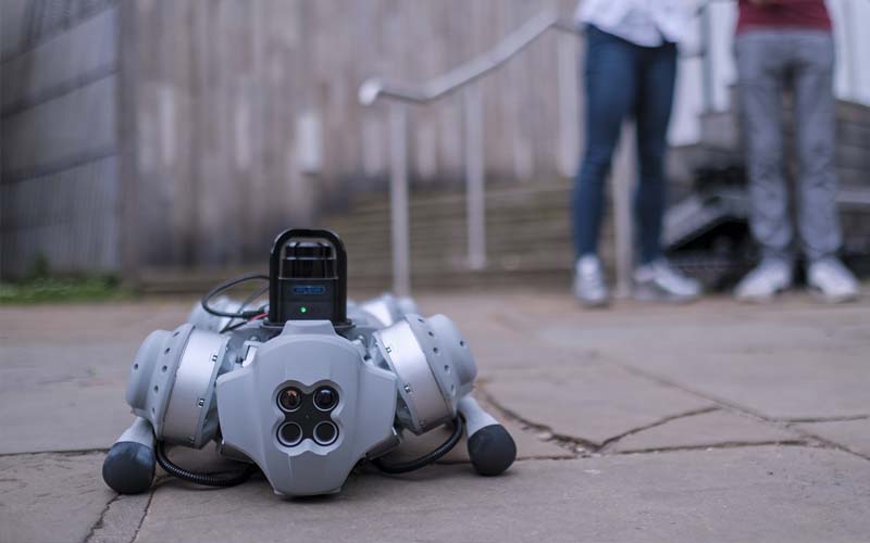 A grey quadrupedal robot crouched down to the floor 