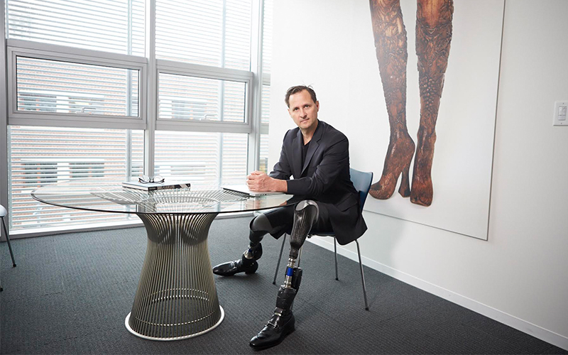 Professor Hugh Herr (MIT) at a table with bionic legs visible.