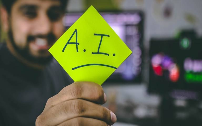 Person holding up a post-it with AI written on it 