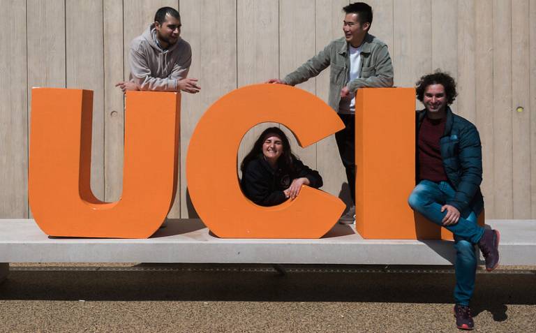 Four students standing with the letters U C and L