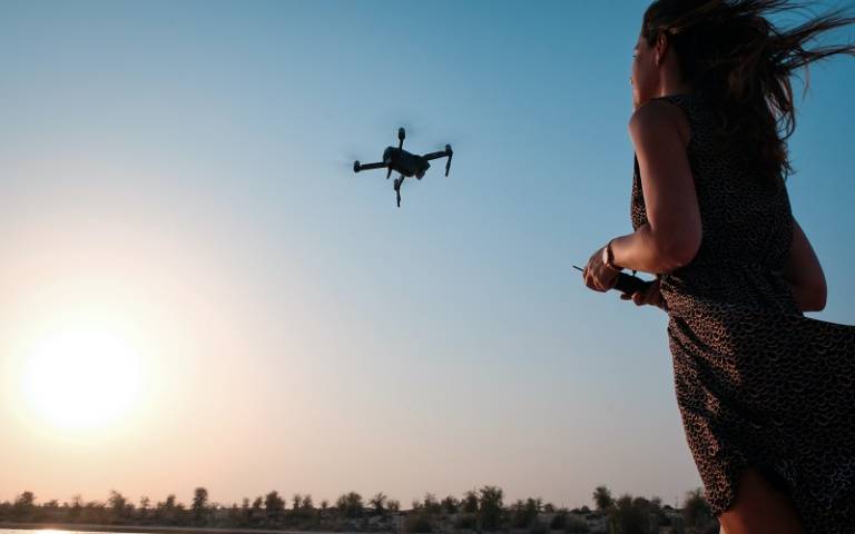 Woman using a drone with sunshine in the background