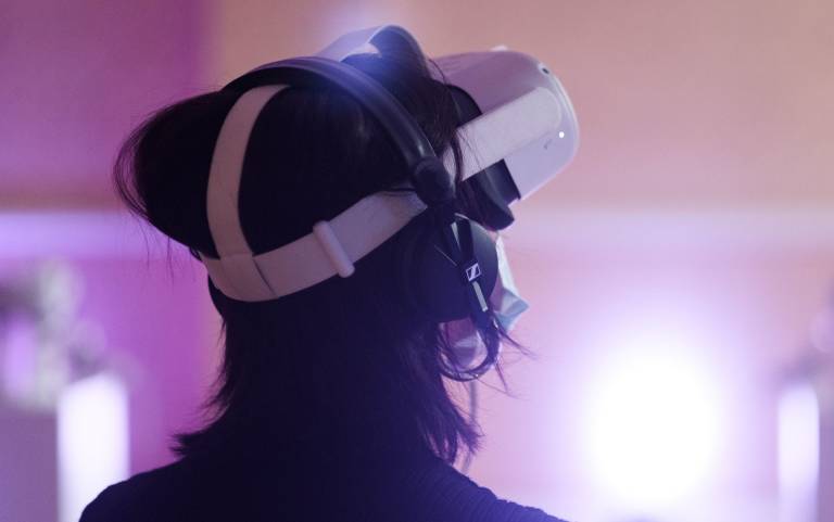 person with VR headset on looking out across brightly lit purple room