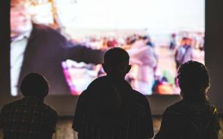 Three figures watching a cinema screen