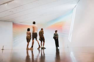 Four figures stand in an exhibition space