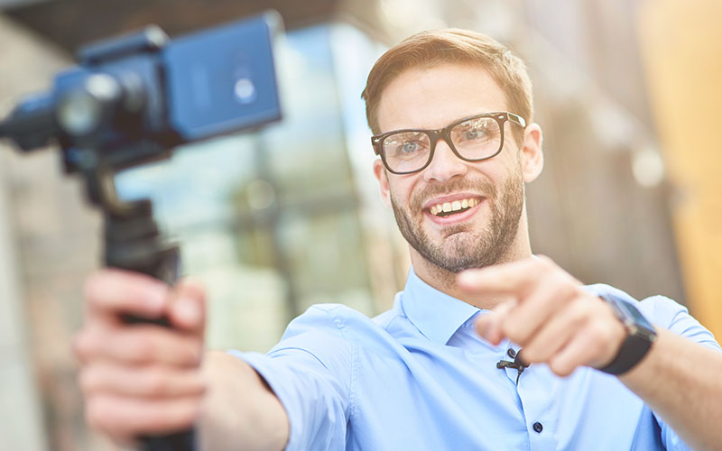 Media Loan - Man wearing glasses taking handheld video selfie