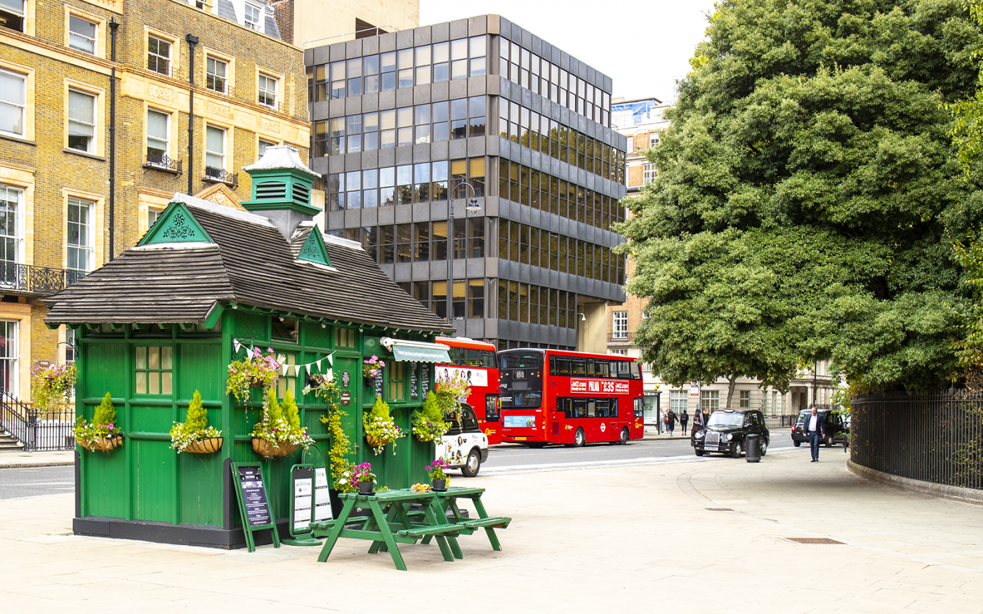 The Little Green Hut café in Russell Square. One of the few surviving Victorian-era Cabmen's Shelters. Black Cabs, red busses and the UCL Institute of Education.