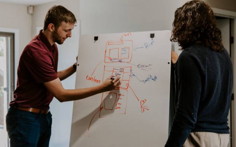 Two people writing on a whiteboard
