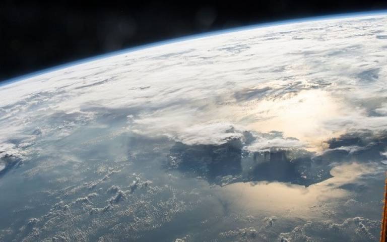Image of Earth taken from outer space. There are large areas of clouds covering the surface of the earth from view. 