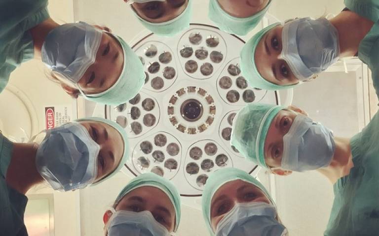 Surgeons in a circle looking down at the camera.