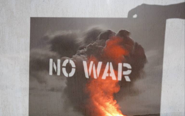 shadow of a sign saying "no war" with an image of an explosion on it