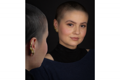 woman wearing gold ear climbers dressed in black looks at herself in the mirror