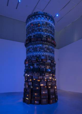 Photograph of a pillar artwork that is covered in old radio players. 