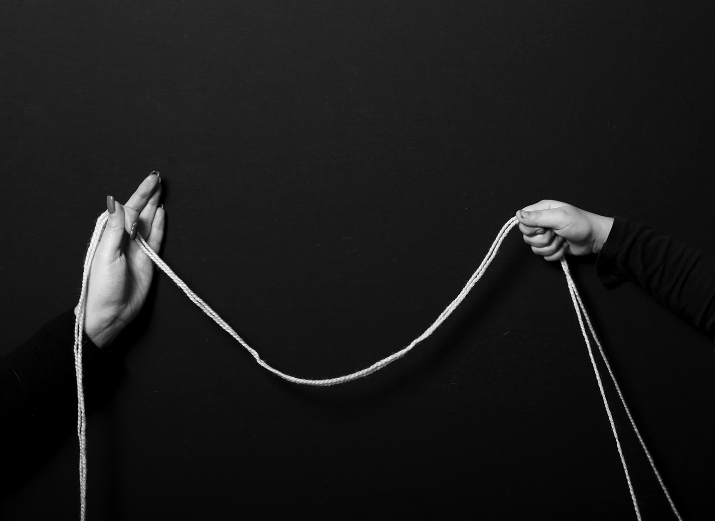 in black and white two hands hold a string between them