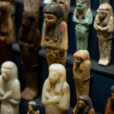 A close-up of a group of ancient Egyptian shabti figurines on a black display mount