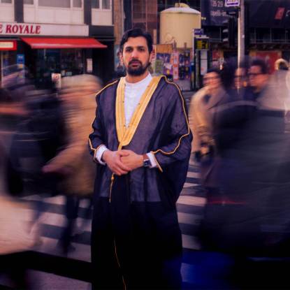 Alaa Abu Diab standing poised and in focus in a street surrounded by the blurred images of other people walking around him