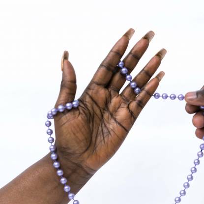 Colour photo of a hand holding purple beads