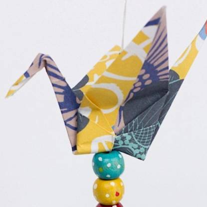 Photograph of an origami crane made from patterned, colourful paper on a white background.