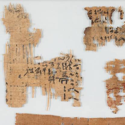Pieces of fragile, damaged papyrus with lettering visible 