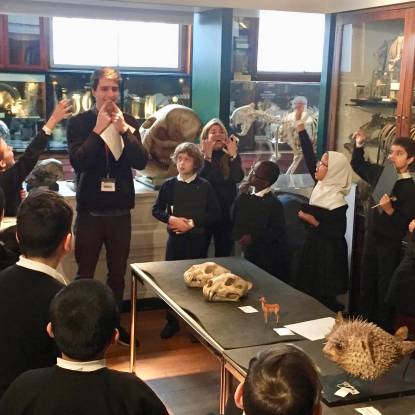 School children in a museum look at animal bones on a table