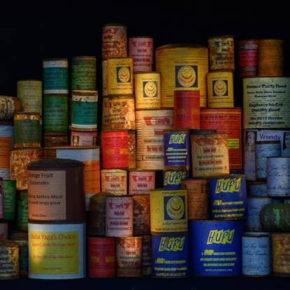 A pile of tin cans with multi-coloured labels against a black background
