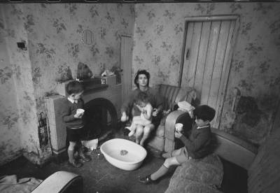 Black and white photo showing a woman sitting inside with children around her