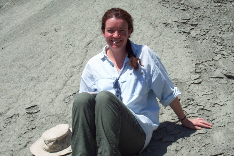 Prof. Bridget Wade sitting on rock smiling towards the camera