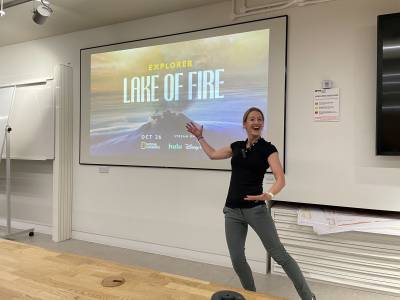 Dr Emma Nicholson standing in front of the 'Lake of Fire' poster.