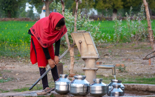 Unidentified Indian girl using hand pump for drinking water