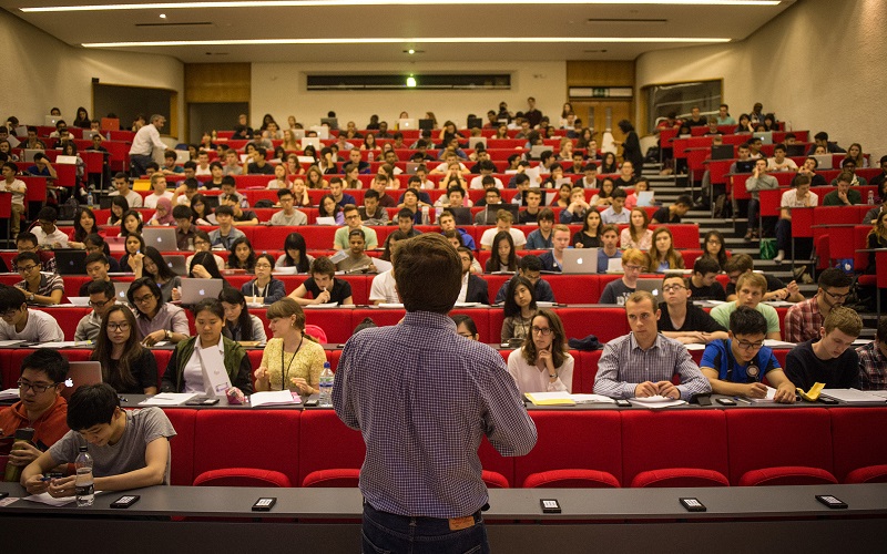 profile of lecturer speaking to a lecture hall of students