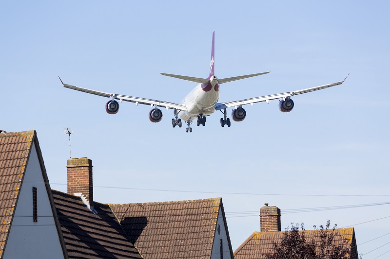 An image of an airplane flying low over a residential neighbourhood