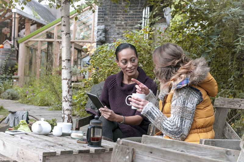 An image of two women conversing while drinking coffee at an outdoor cafe