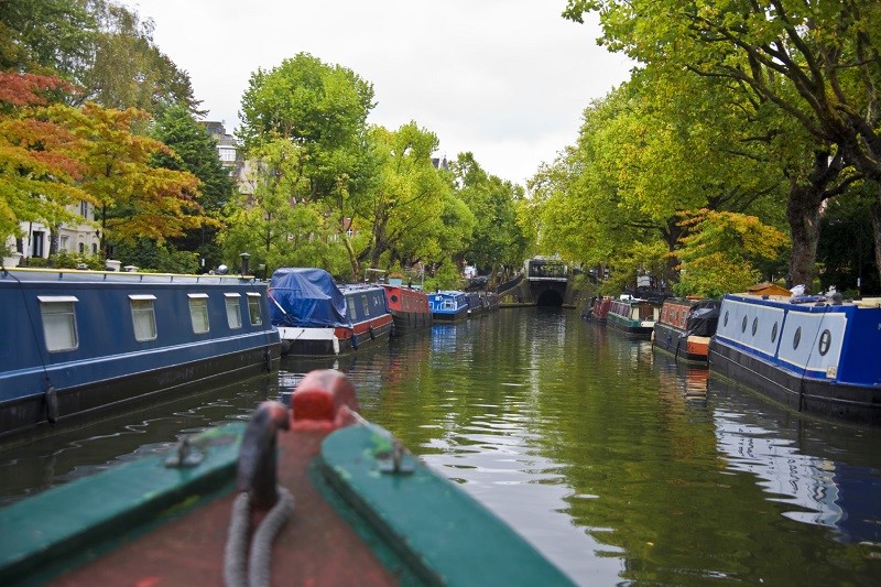 An image of the view from a canal boat, looking down a tree-lined canal