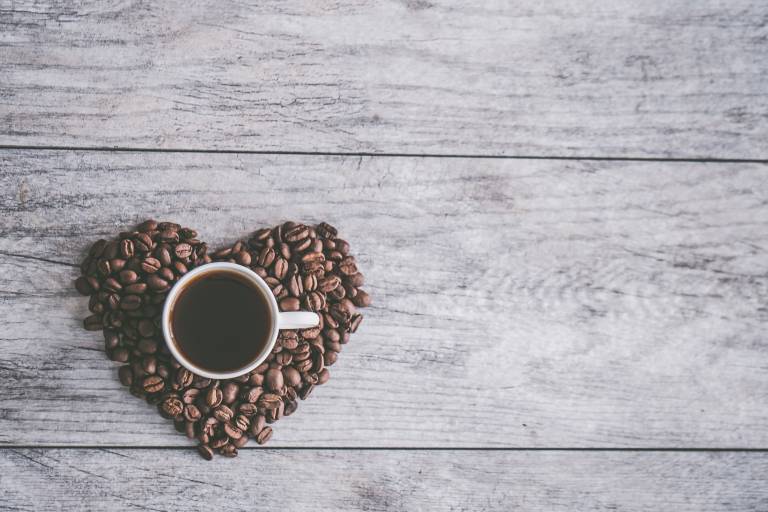 A mug of coffee in a heart-shape of coffee beans.