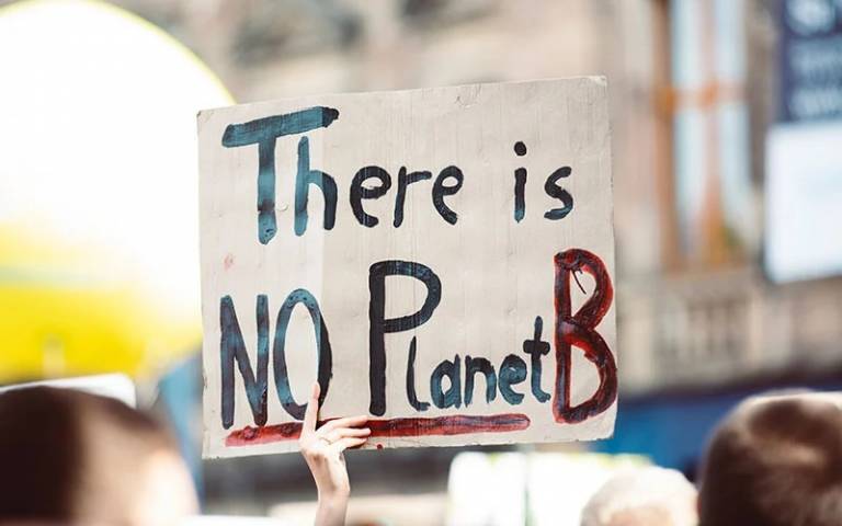A hand holds a placard with the words 'There is no Planet B'