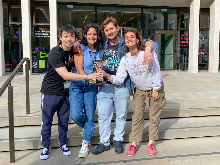 4 students holding the Engineering Cup 2022 in front of the UCL Student Centre