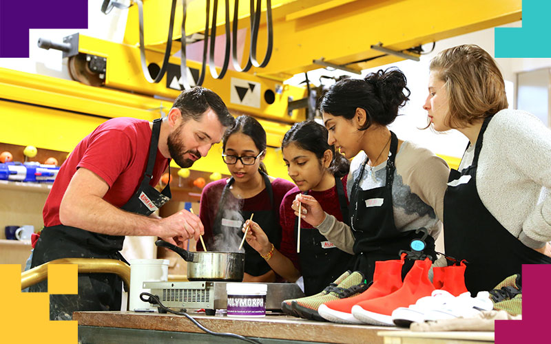 A making lab demonstrator and a group of students mix chemicals in a saucepan on a desk with shoes on it.