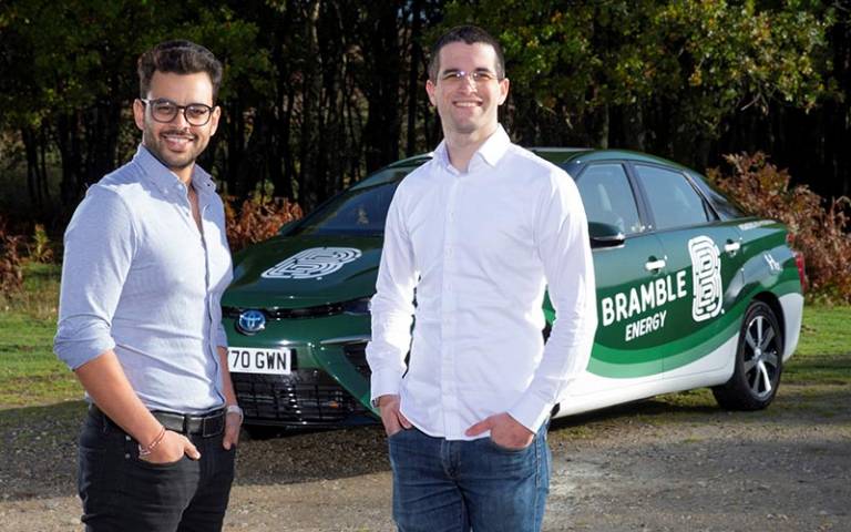 Two men stand in front of a car branded with Bramble Energy