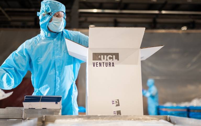 A person in protective clothing, packing UCL Ventura CPAP devices into a big box