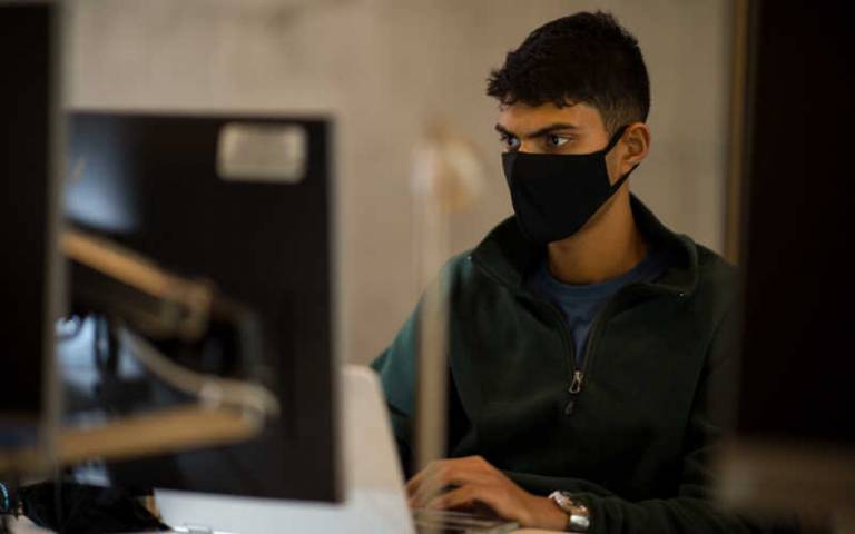 Young person wearing a facemask, sitting at a computer