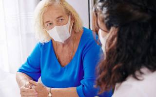Social care worker talking to a patient, both wearing face masks