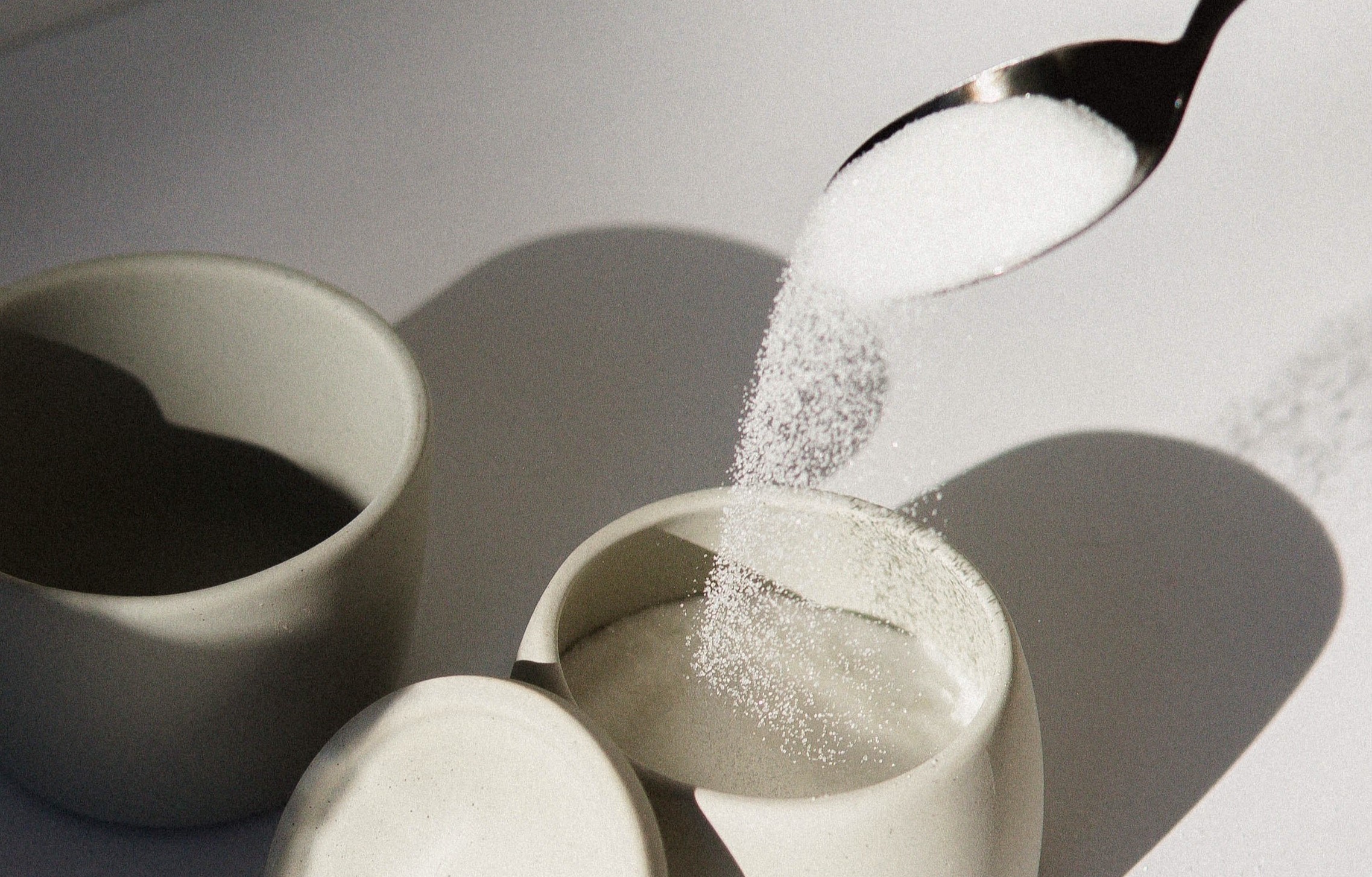 Photograph of sugar being poured into a bowl.