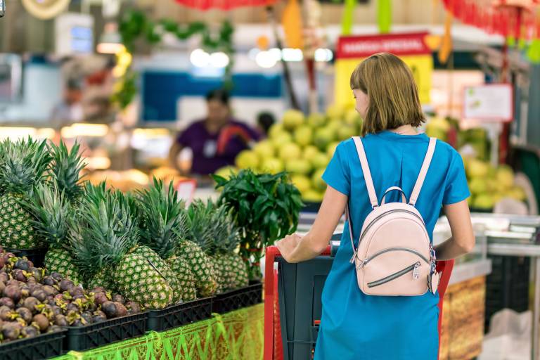 Image of woman at supermarket looking at pineapples