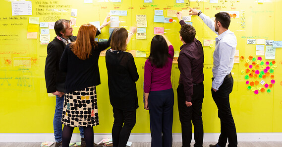 A group of people examining a wall of post-its