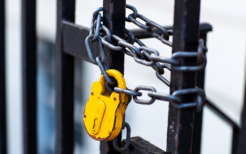 a yellow padlock secures a chain on a railing