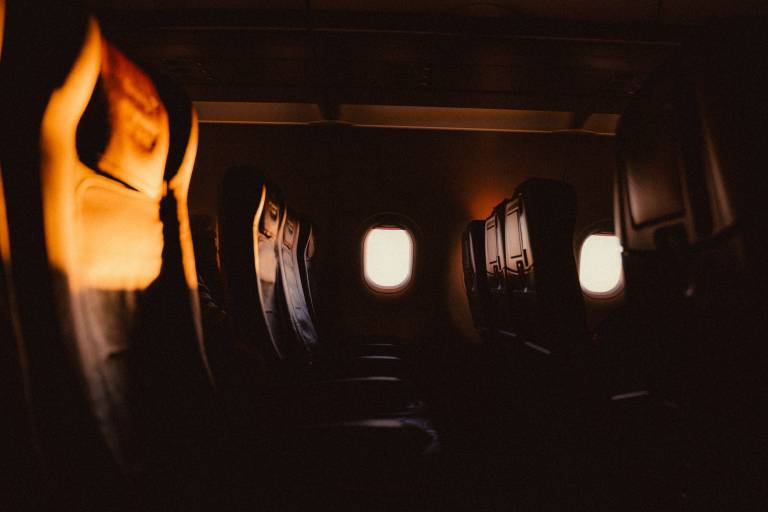 A row of empty seats on an aeroplane, lit up by the glow of the setting sun.