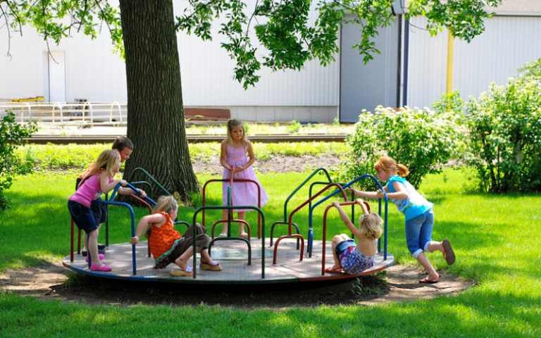 a group of nursery school age children playing on a roundabout