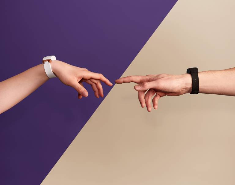 Two hands reaching out to touch one another with a smart watch on their wrist.